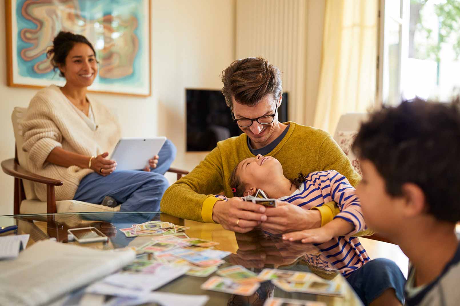 Eine Familie sitzt im Wohnzimmer und spielt Karten