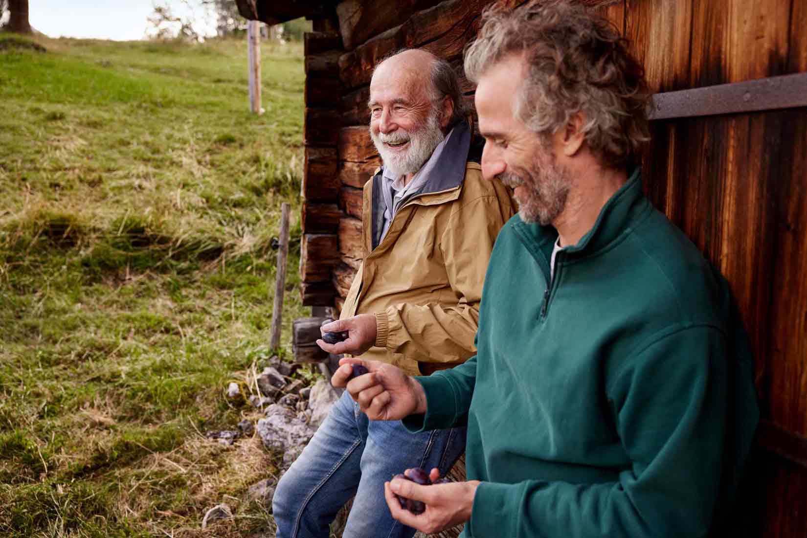 Ein älterer Vater unterhält sich mit seinem Sohn auf einer Alm