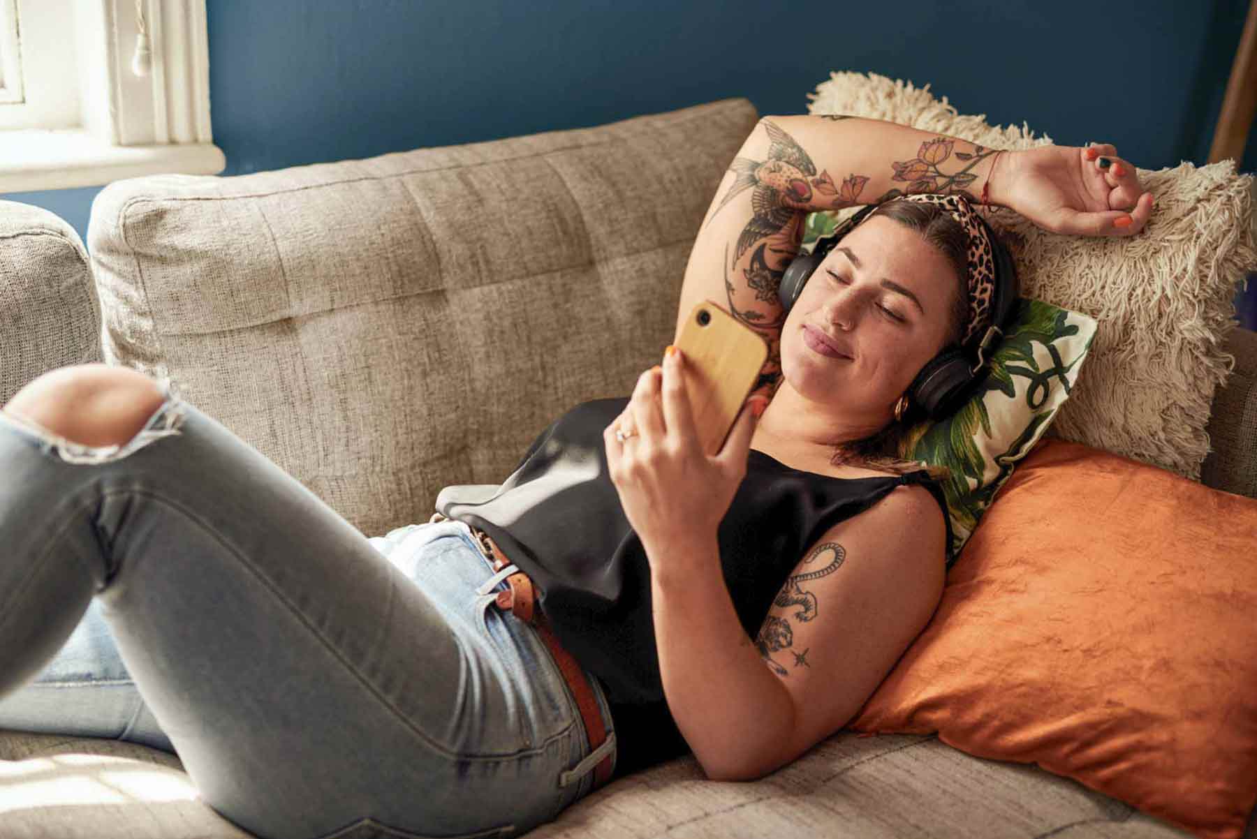 Eine junge Frau liegt auf dem Sofa mit ihrem Smartphone